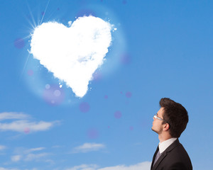 Handsome man looking at white heart cloud on blue sky