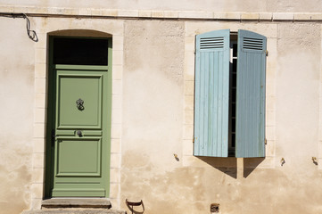 façade de maison avec porte verte et volet bleu