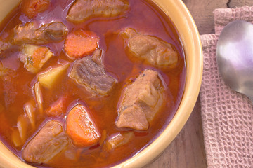 Pork stew in ceramic bowl on wooden table