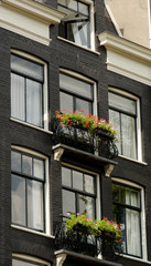 Fototapeta na wymiar Flower baskets over canal in Amsterdam