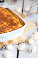meat lasagna with mushrooms in a white bowl on a blackboard
