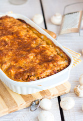 meat lasagna with mushrooms in a white bowl on a blackboard