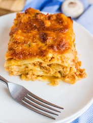 piece of meat lasagna with mushrooms on a round plate
