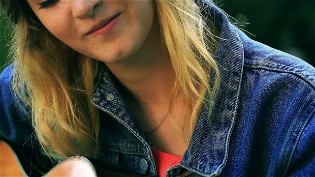 Teenage girl playing on the guitar in the park, steadycam shot