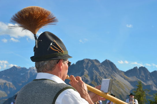 Alphornspieler mit Hut im Gebirge