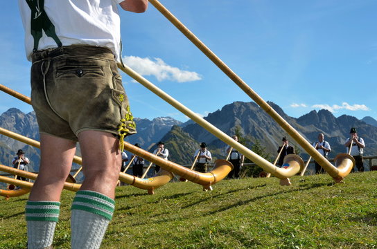 Alphornspieler mit Tracht im Gebirge