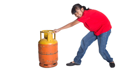 Young Asian girl moving an old cooking gas propane cylinder 
