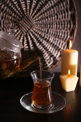 Tea pouring into glass cup on dark background