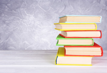 Books on wooden table on light background