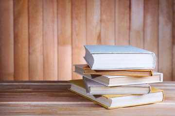 Books on wooden table on wooden wall background
