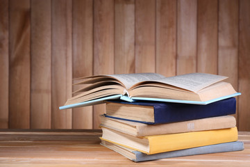 Books on wooden table on wooden wall background