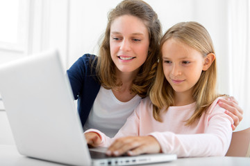 Attractive woman and little sister using laptop