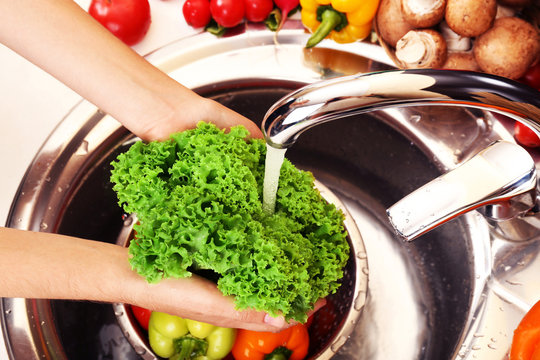 Woman's Hands Washing Vegetables In Sink In Kitchen