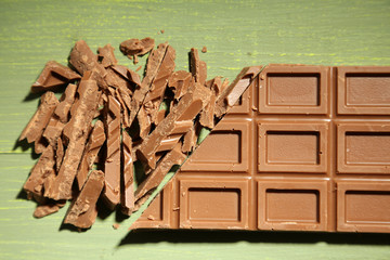 Milk chocolate bar on color wooden background