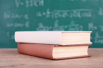 Books on wooden table on blackboard background