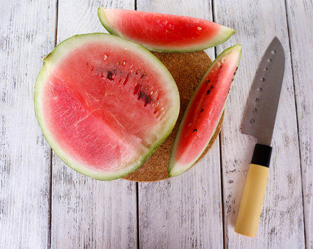 Watermelon and knife on cutting board on wooden background