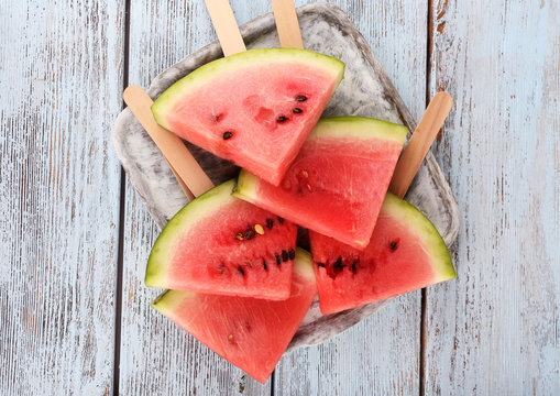 Slices of watermelon on tray on wooden background