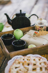 Homemade apple pie, apples and autumn leaves on the wooden table