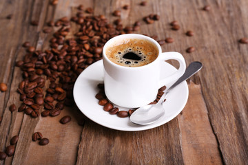 Cup of coffee and coffee beans on wooden background