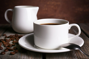 Cup of coffee with cream in milk jug and coffee beans