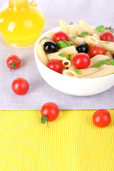Pasta with tomatoes, olives, olive oil and basil leaves in bowl