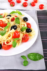 Spaghetti with tomatoes, olives and basil leaves