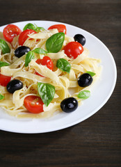 Spaghetti with tomatoes, olives and basil leaves