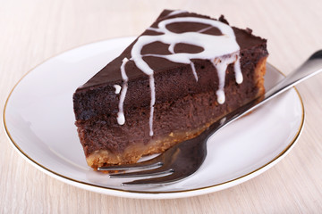 Piece of chocolate cake on saucer on wooden background