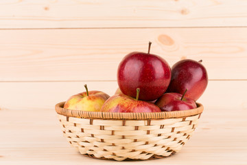 Fresh red apples in basket on wood.