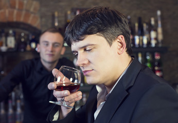 man drinking brandy near the bar