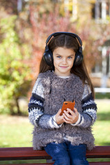 Beautiful little girl listening to music on headphones