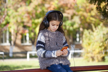 Beautiful little girl listening to music on headphones