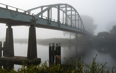 Old iron arch bridge over a small river
