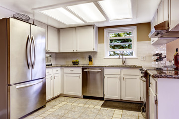 White kitchen room with steel appliances and tile backsplash tri