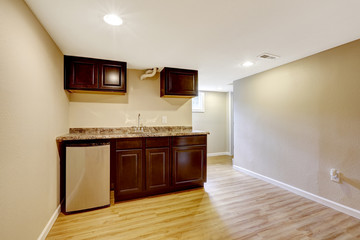 Empty basement room with dark brown kitchen cabinets