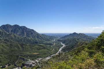 Mountain valley. On the horizon, the skyscrapers of  Beijing