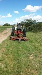 Mowing grass with a tractor, going away, rear view 