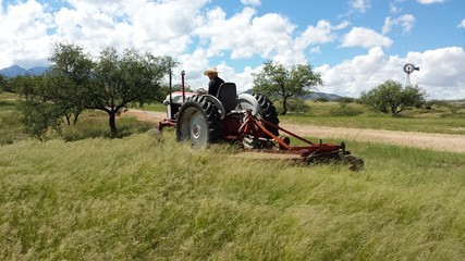Fototapeta na wymiar Mowing in the Arizona grasslands with tractor and brushhog