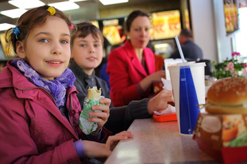 Mother with two kids have snack in fast food restaurant