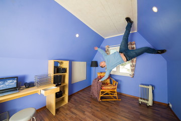 Man in jeans running on ceiling upside down at inverted house