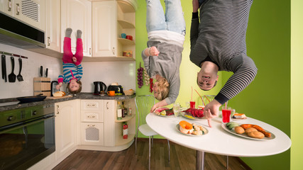 Family upside down in kitchen with table and dishes