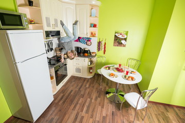 Mother and daughter sitting at shelves upside down in kitchen