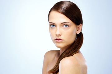 Obraz premium Portrait of a cute young girl with fresh skin on blue background