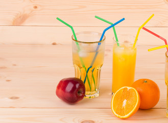 Orange and apple juices on wooden table.