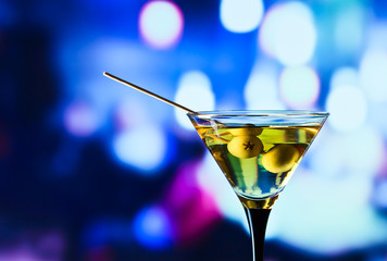 glass with martini and green olives