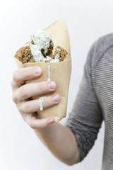 male hand holding falafel balls with dripping yogurt sauce