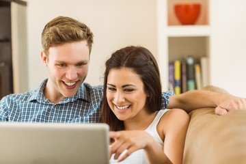 Happy young couple relaxing on the couch with laptop