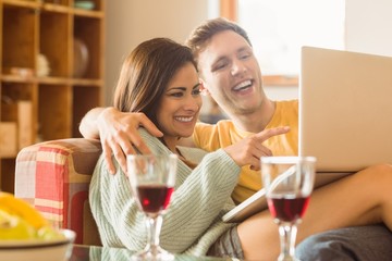 Young couple cuddling on the couch with laptop