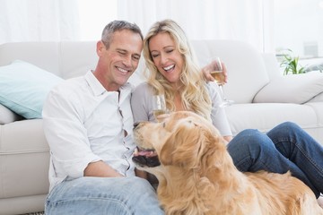 Couple drinking champagne with their dog in front of them