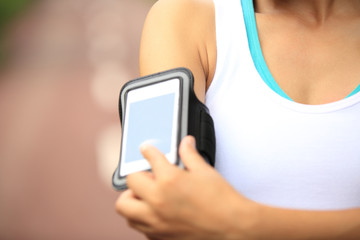 woman runner listening to music in headphones from smart phone m